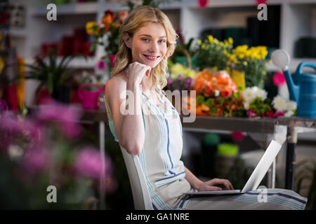 Smiling female florist using laptop in florist shop Stock Photo