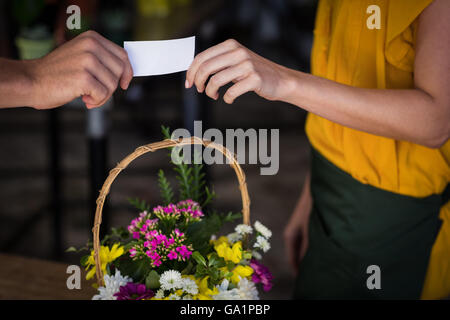 Female florist giving visiting card to customer Stock Photo