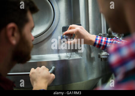 Maintenance workers examining brewery machine Stock Photo