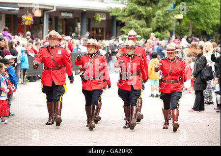 A Troop of RCMP Police officers in traditional red serge march in the 2016 Whistler Canada Day Parade. Stock Photo