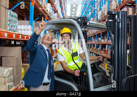 Worker driving forklift discussing with businessman Stock Photo