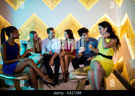 Group of smiling friends interacting while having a glass of champagne Stock Photo