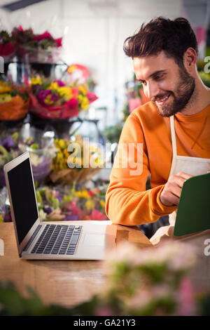 Male florist checking order in laptop Stock Photo