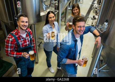 Brewers holding glass of beer standing at brewery Stock Photo