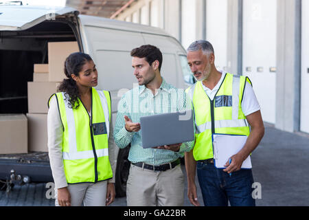 Manager is talking and showing something on laptop to the workers Stock Photo