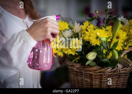 Female florist spraying water on flowers Stock Photo