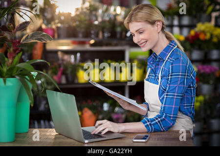 Female florist using laptop while holding clipboard Stock Photo