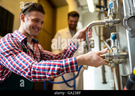 Maintenance workers examining brewery machine Stock Photo