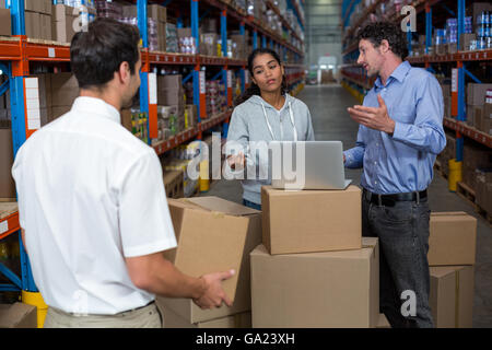 Workers talking and working with a laptop put on cardboard Stock Photo