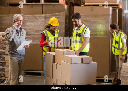 Manager is talking on the phone next to the workers Stock Photo