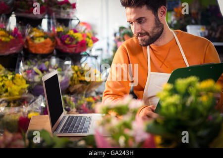 Male florist checking order in laptop Stock Photo