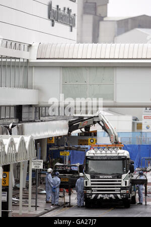 Police forensic officers look on as the wreckage of the Jeep Cherokee is removed from the scene of yesterday's dramatic attack on the terminal building at Glasgow Airport. Stock Photo
