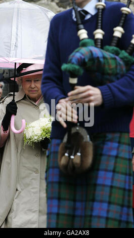 Britain's Queen Elizabeth II holds an umbrella and walks behind a man playing the bagpipes during a visit to Haddington, East Lothian. Stock Photo