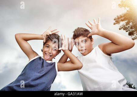 Two happy boys having fun outdoors, making faces to the camera, best friends enjoying holidays in a summer camp Stock Photo