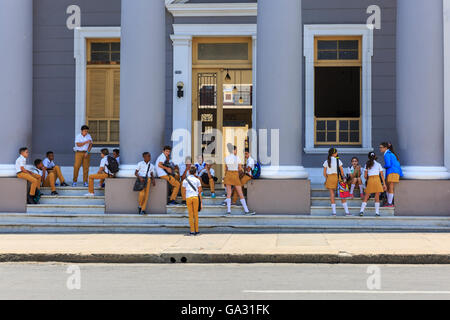 School children in uniform wait outside their school building in Cienfuegos,  on the South Coast of Cuba Stock Photo