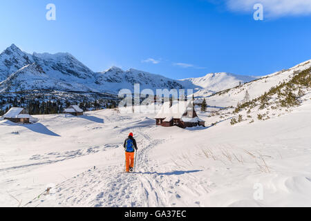 Young woman backpacker tourist walking to mountain huts in winter landscape of Gasienicowa valley, Tatra Mountains, Poland Stock Photo