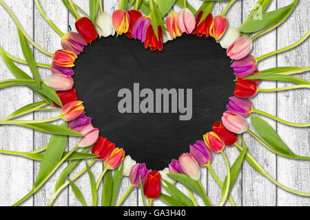 heart shaped out of tulips on white wooden background with slate Stock Photo