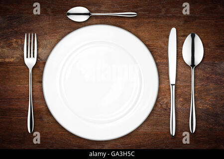 place setting with empty dish fork spoon and knife on wooden background Stock Photo