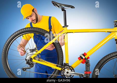 bicycle mechanic mounting brake caliper on yellow mountain bike Stock Photo