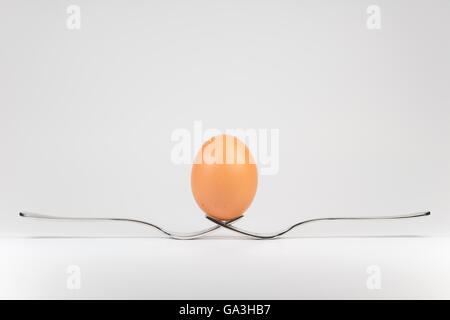 Balancing egg on two cooperating metal forks Stock Photo