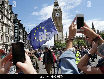 People take photos of a European Union flag in front of Big Ben, as Remain supporters demonstrate in Parliament Square, London, to show their support for the EU in the wake of Brexit. Stock Photo