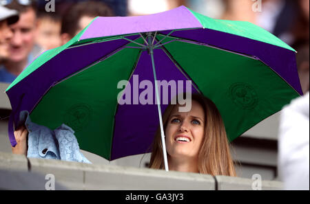 Kim Murray shelters under an umbrella as rain stops play on centre court on day Six of the Wimbledon Championships at the All England Lawn Tennis and Croquet Club, Wimbledon. Stock Photo