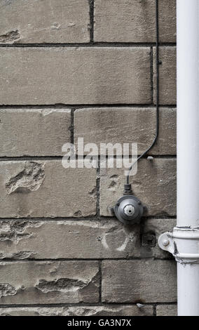 Old retro style, vintage electrical light switch ON OFF with black wires on a old stone wall background Stock Photo
