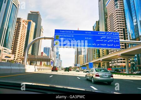 City of Dubai. Road signs driving along city centre Sheikh Zayed Road. Al Yaquob Tower in distance. United Arab Emirates Stock Photo