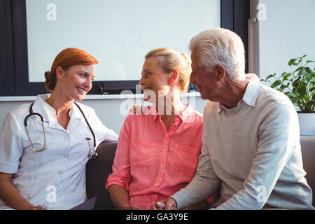 Nurse and senior couple sitting on a couch Stock Photo