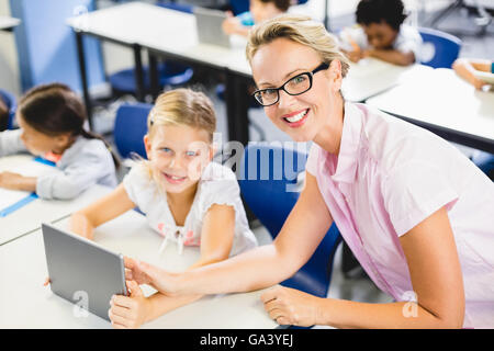 Schoolgirl and teacher using digital tablet in classroom Stock Photo