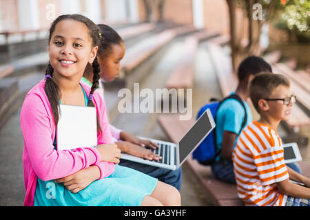 Kids sitting on bench and using laptop Stock Photo