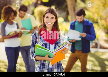 Portrait of college girl holding notes with friends in background Stock Photo