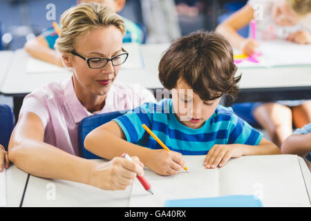 Teacher helping a boy with studies in classroom Stock Photo