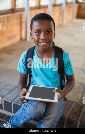 Schoolboy sitting on staircase using digital tablet Stock Photo