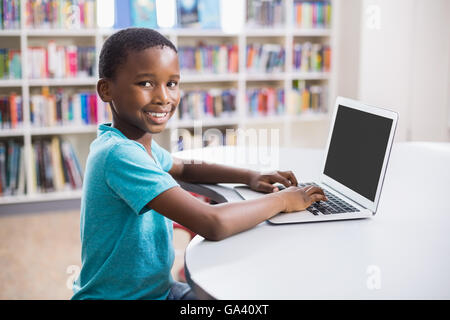 Schoolboy using laptop in library Stock Photo