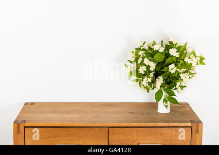 Commode with flowers on a white wall interior design Stock Photo