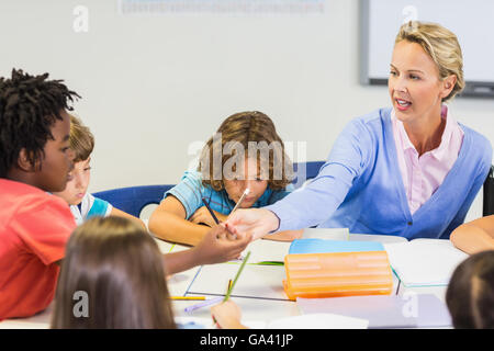 Teacher helping schoolgirl with her homework in classroom Stock Photo