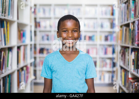 Happy schoolboy standing in library Stock Photo