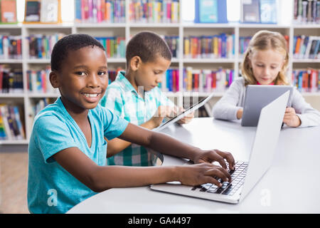 Kids using laptop and digital tablet in library Stock Photo