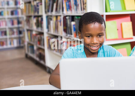 Schoolboy using laptop in library Stock Photo