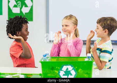 Kids giving high five to each other in classroom Stock Photo