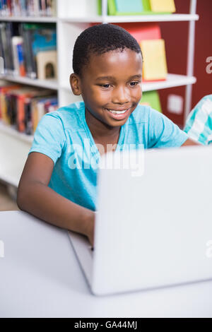 Schoolboy using laptop in library Stock Photo