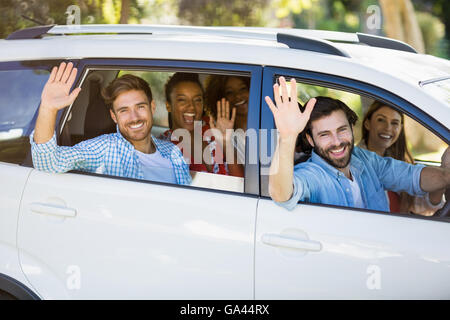 Group of friends waving hands from car Stock Photo