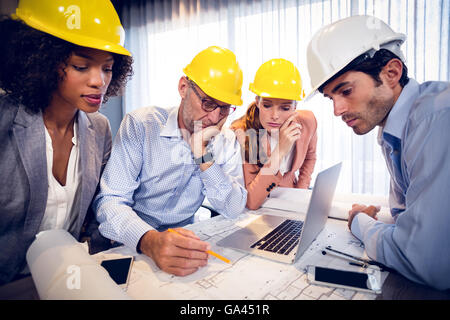 Four architects discussing blueprints in meeting Stock Photo