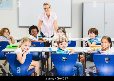 Teacher and kids smiling in classroom Stock Photo