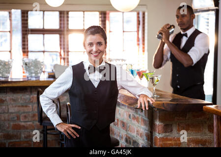 Smiling female bartender standing at bar counter Stock Photo