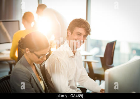Businessman working on computer with coworker Stock Photo