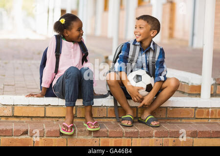 Smiling kids sitting on stairs at school Stock Photo