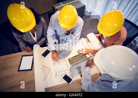 Four architects discussing blueprints in meeting Stock Photo