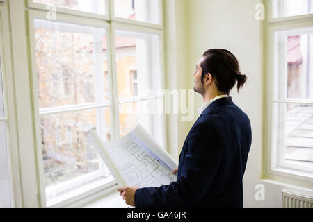 Interior designer with blueprint looking though window Stock Photo